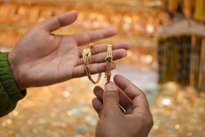 Una mano probándose una lujosa pulsera de oro