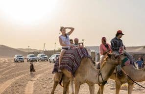 Turistas montando en camello en el desierto de Dubái