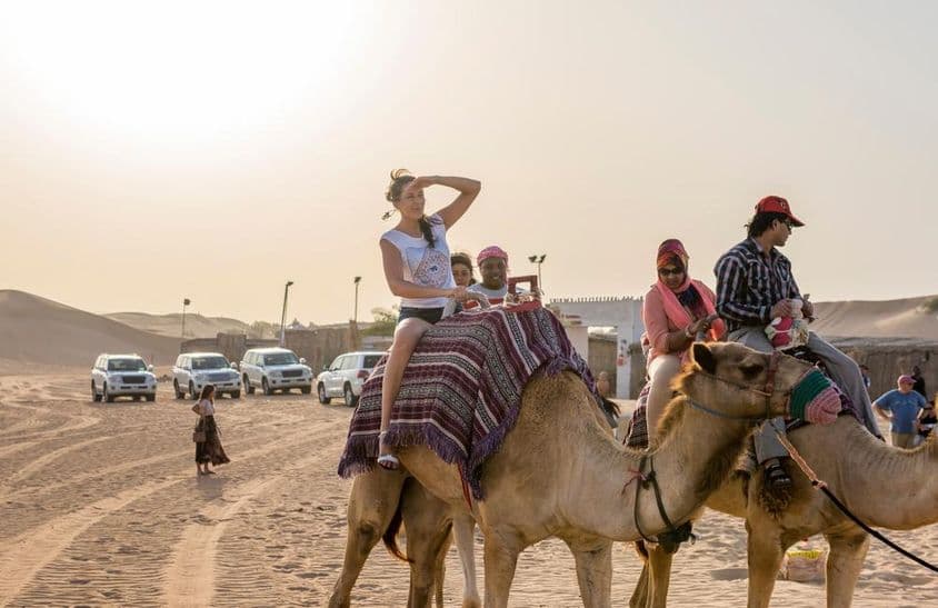 Turistas montando en camello en el desierto de Dubái