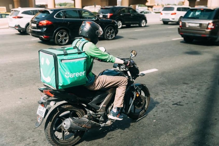 Repartidor entregando comida en un scooter.