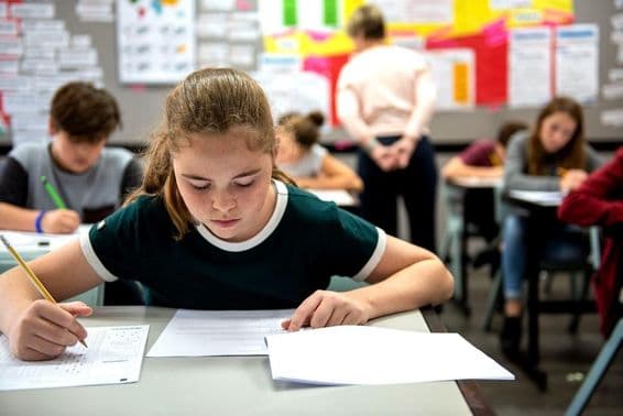 Estudiantes tomando exámenes en un aula.