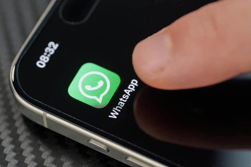 Dedo tocando el ícono de la aplicación WhatsApp