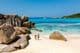 Dos viajeros caminando sobre las suaves arenas blancas de la playa Anse Cocos en Seychelles.