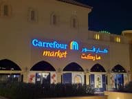 Logotipo iluminado del mercado Carrefour con nombre de marca en árabe