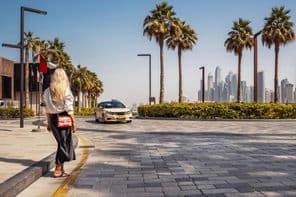 Mujer de pie en la calle, esperando un taxi.