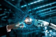 Manos de robot y humano conectando un circuito de IA