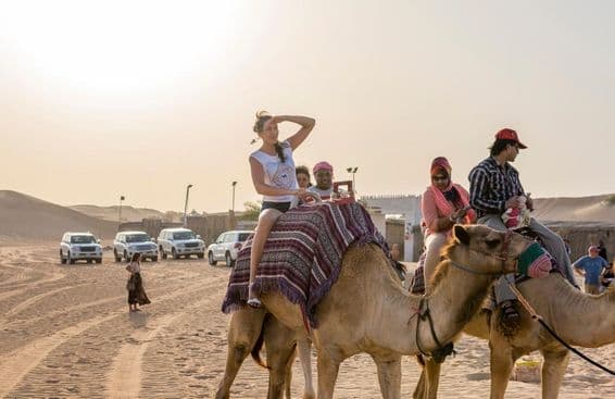 Turistas montando camellos en el desierto.