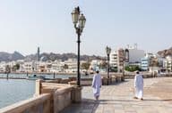 Hombres con indumentaria tradicional omaní en el malecón de Mascate.