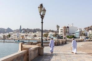 Hombres con indumentaria tradicional omaní en el malecón de Mascate.
