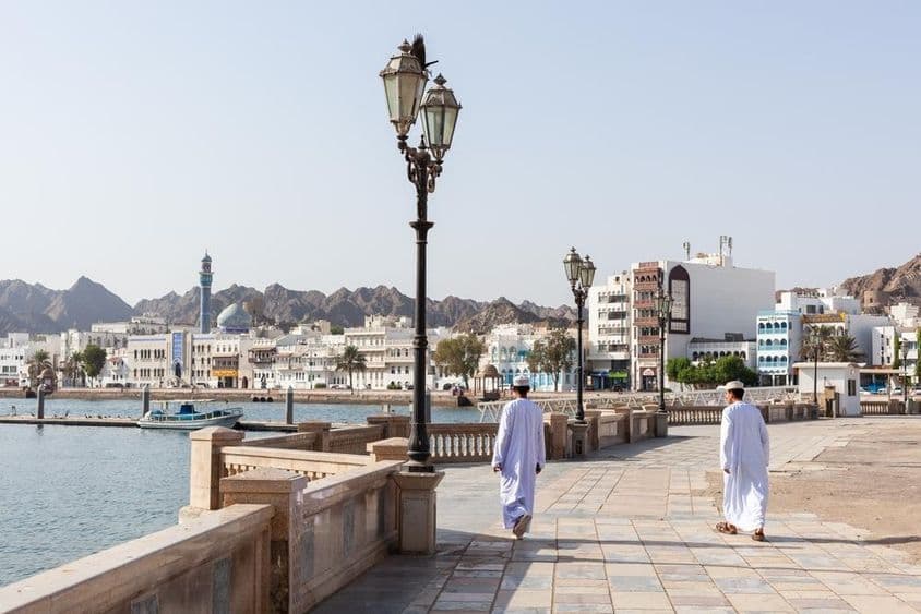 Hombres con indumentaria tradicional omaní en el malecón de Mascate.