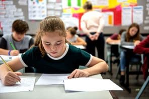 Estudiantes realizan exámenes en un aula.