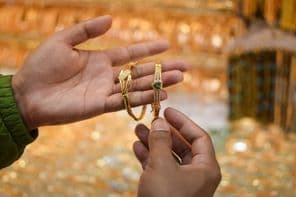 Una mano probándose una pulsera de oro de lujo