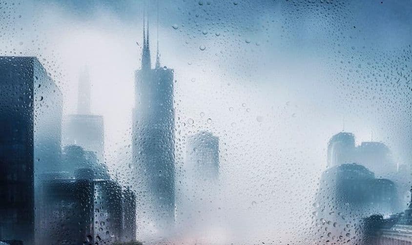 Vista de una ciudad a través de una ventana en una noche lluviosa