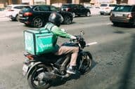 Repartidor entregando comida en scooter.