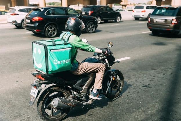 Repartidor entregando comida en scooter.