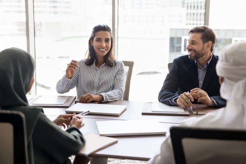 Mujer de negocios española conversa con socios árabes en atuendo musulmán