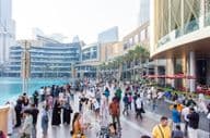 Una multitud diversa de turistas y locales camina por el concurrido paseo marítimo frente al Dubai Mall.