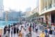 Una multitud diversa de turistas y locales camina por el concurrido paseo marítimo frente al Dubai Mall.